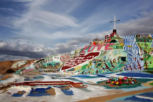 One of the coolest places in California has to be Salvation Mountain. Absolutely surreal location!
The road to Salvation Mountain, Palm Springs, offers one of the trendiest and coolest Instagram-able spots in the Golden State. Unlike others, this unique mountain is man-made, colorful, and equipped to redeem all its visitors.
To give you a little backstory, when Leonard Knight first started building this with his bare hands, he wasn’t planning on devoting 28 years of his life to it. Paints, donations, and its non-profit caretakers preserve this enormous artifact as a “roadside” museum.
Also, If you’re up for an incredible weekend road trip, instead of heading straight to the Salvation Mountain consider taking a detour to Joshua Tree National Park. Being the gift that keeps on giving, the Sonoran Desert is home to the world's rarest cactus tree, which barely grows 3 inches a year. Take your snacks and water, stock up on fuel or gas, and be an eye-witness to this spiky treasure. The fees change per season and year, so be sure to dig your info out in advance.