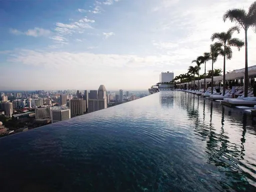 Did you ever dive into the sky??
The infinity rooftop pool Marina Bay Sands is well known over the whole world. And for good reasons! This is the world’s longest elevated pool, a 150 meter long bliss of glittering water, set almost 200 meter above sea level.
Surrounded with tall palm trees, several levels of comfy sun loungers and (most of all) some amazing views over the Singapore skyline, the rooftop swimming pool is split into three sections: an adults-only area, a family-friendly section, and a dedicated children's pool.
Opposite to the large infinity pool you also find a couple of smaller jacuzzis with views over the ocean, which helps making this impressive rooftop venue to one of the most iconic places to take pictures when in Singapore. The rooftop pool is only open to guests staying at the hotel, but there are several rooftop bars and restaurants on the same floor that are open to all.